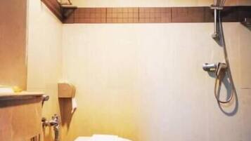 A bathroom with a toilet, a shower, and a towel rack.