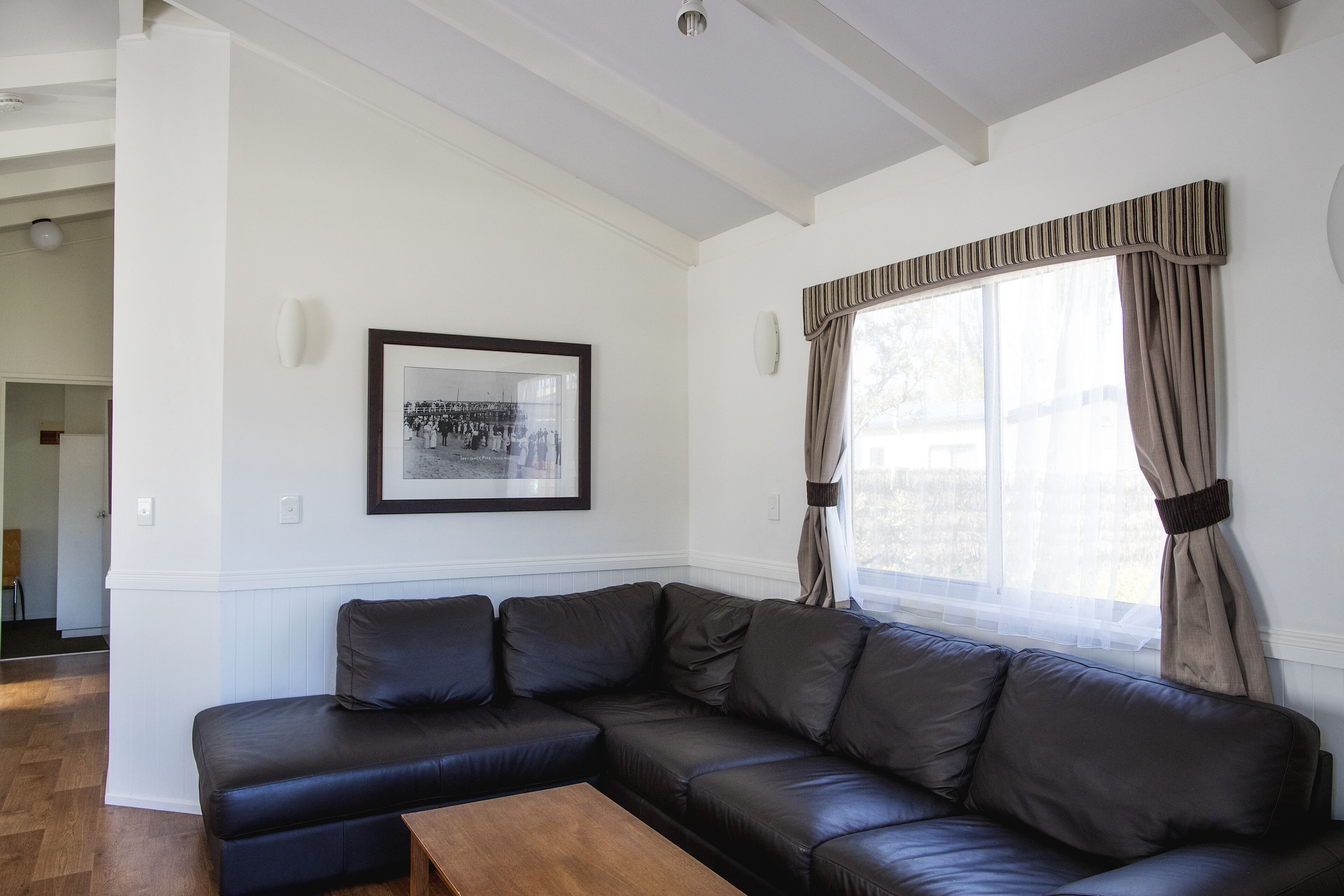 A living room with a dark leather sectional sofa, a wooden coffee table, and a framed picture on the wall.