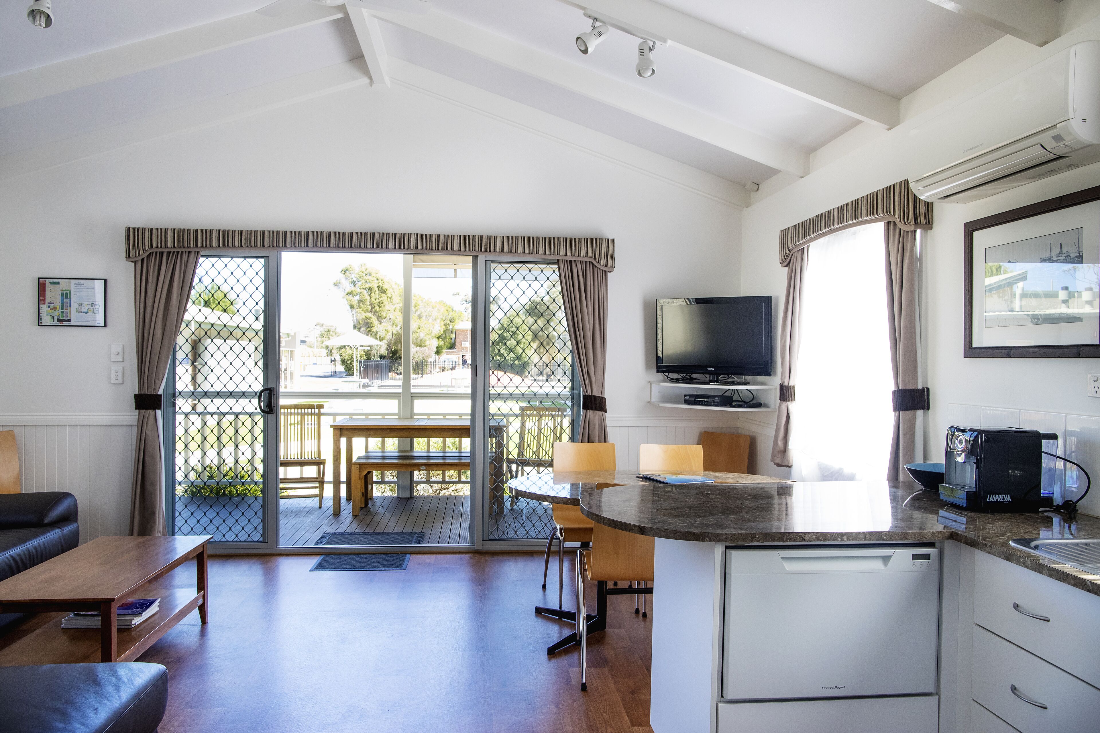 A modern kitchen with a built-in dishwasher, a dining area with a table and chairs, and a large sliding glass door leading to an outdoor patio.