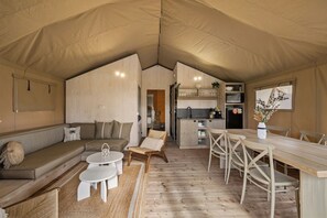 A tented accommodation with a sofa, dining table, chairs, a kitchen area, and a small seating area. - BIG4 Ingenia Holidays Inverloch (Inverloch)