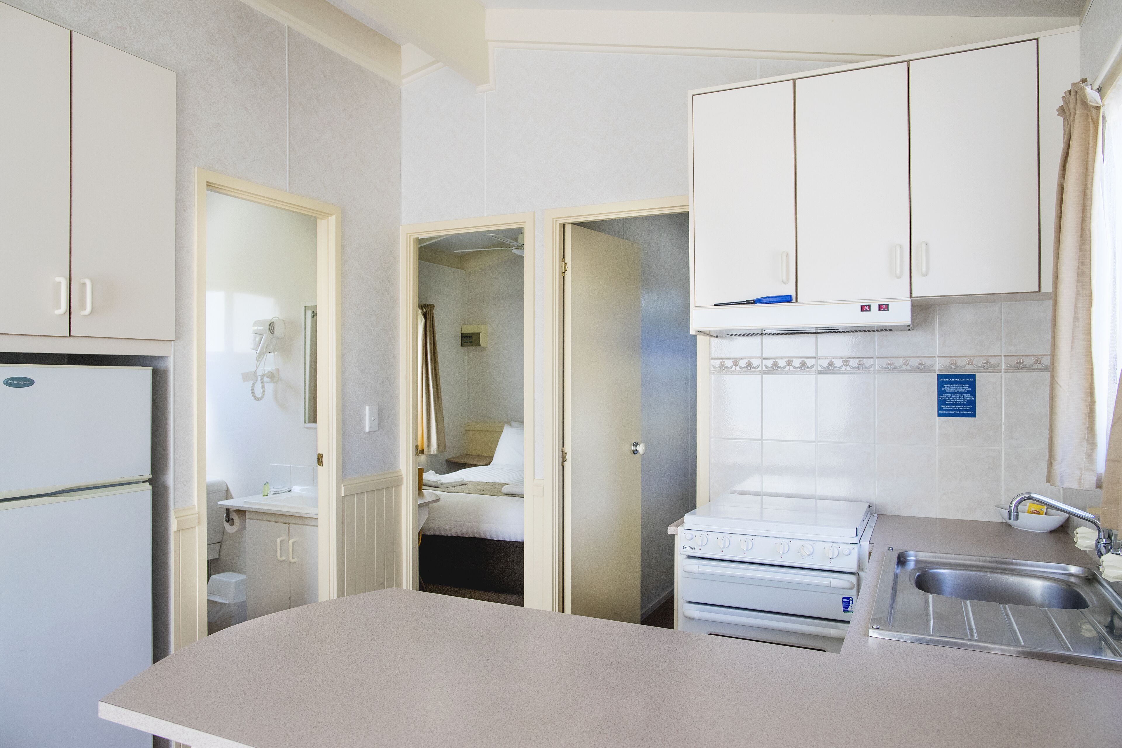 A compact kitchen with a refrigerator, stove, sink, and cabinets.
