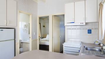 A compact kitchen with a refrigerator, stove, sink, and cabinets.