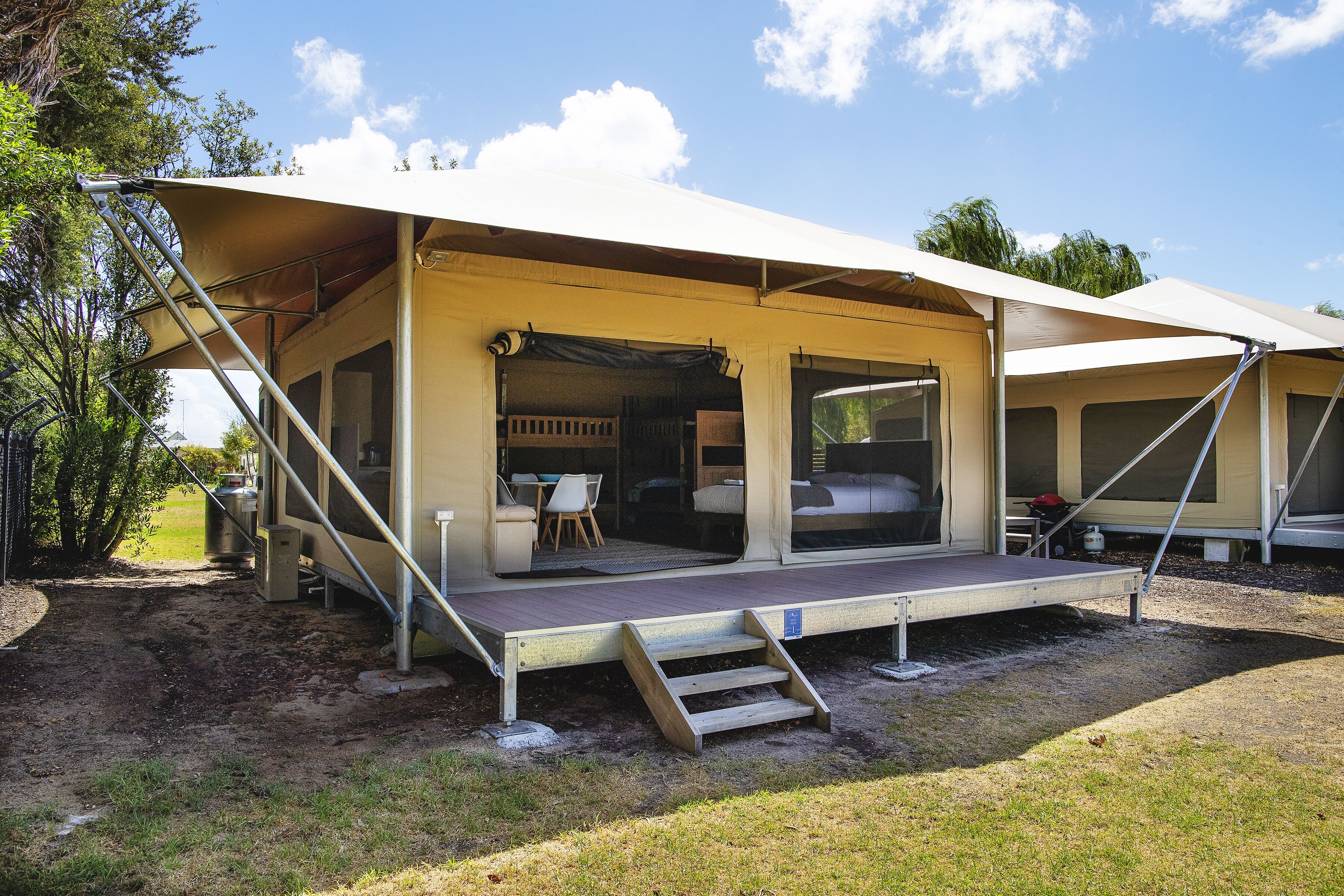 A caravan with a covered porch, a set of steps leading to the entrance, and a small outdoor seating area.
