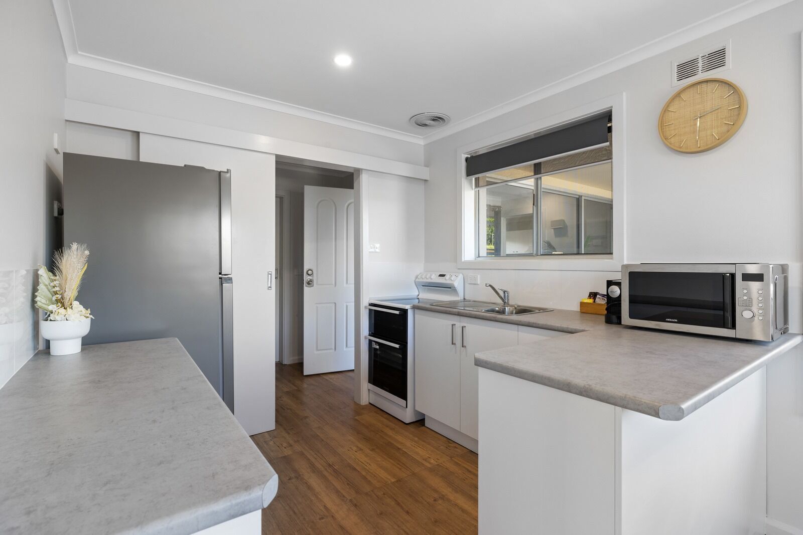 Una cocina moderna con microondas integrado, un fregadero y una ventana sobre la encimera.