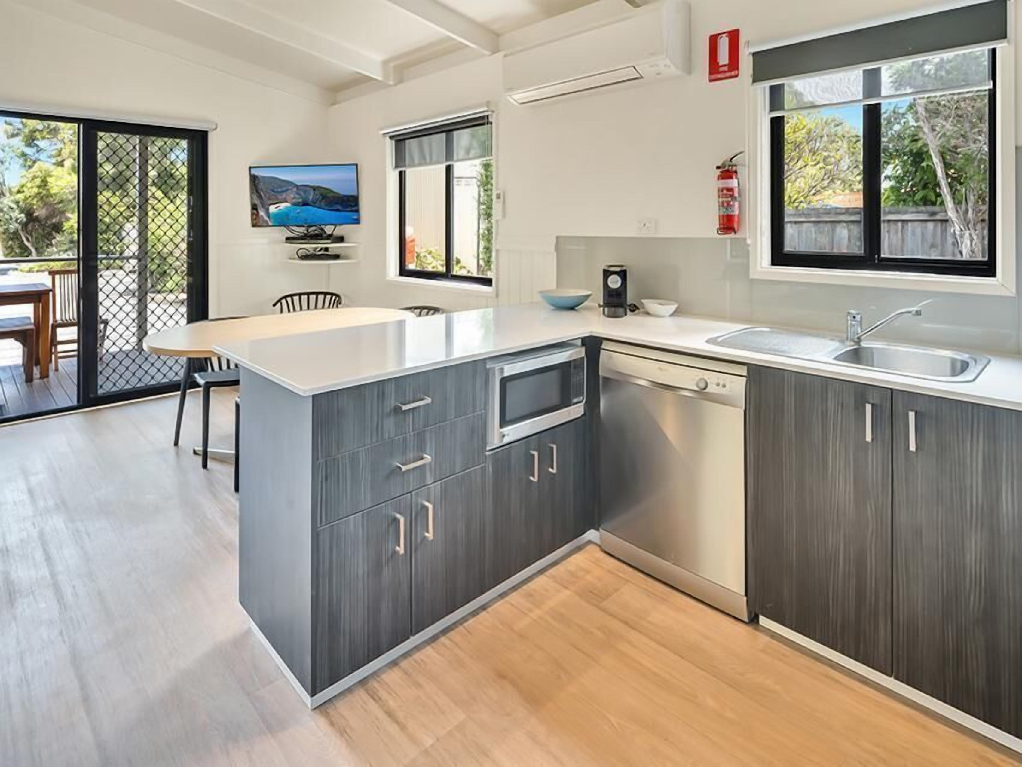A modern kitchen with a large island, a dining area with a table and chairs, and a view of the outdoors.