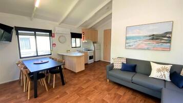 Un espace de vie compact comprenant un coin repas, une kitchenette et un canapé agrémenté de coussins décoratifs.