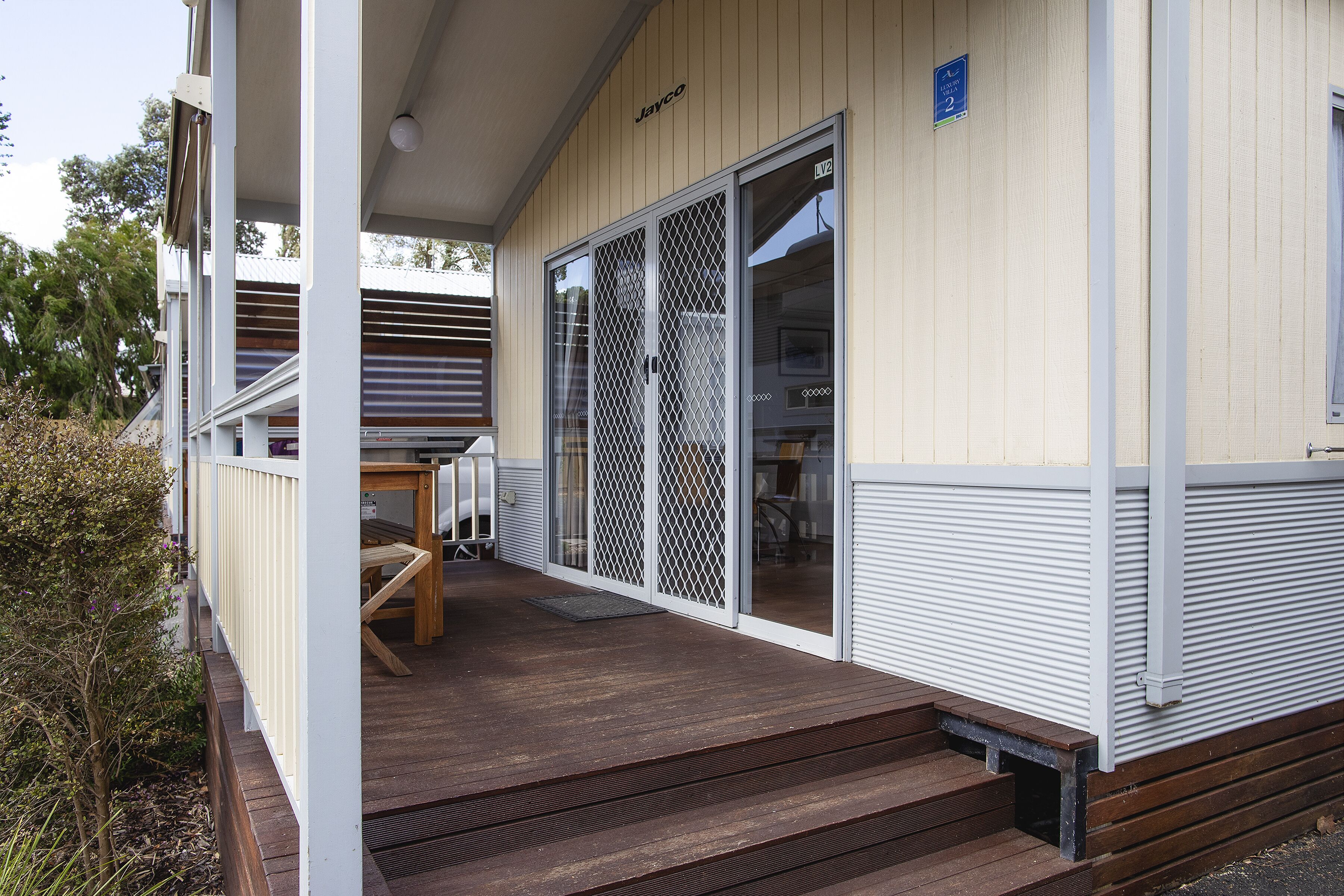 Une terrasse en bois avec une porte-fenêtre coulissante donnant sur un porche abrité.