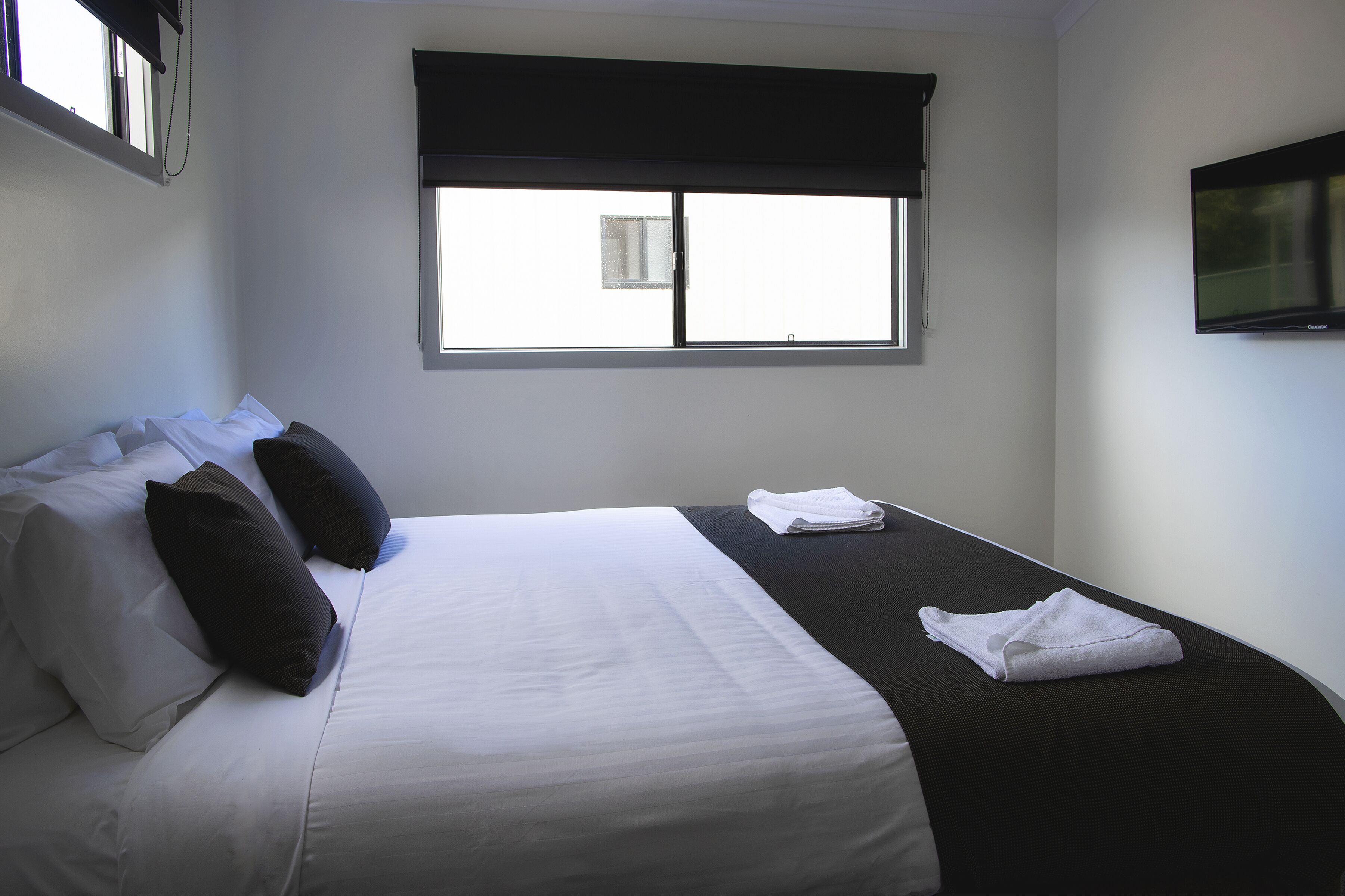 A hotel room with a bed, a window, and a TV.