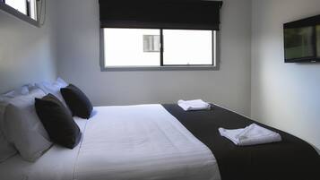 A hotel room with a bed, a window, and a TV.