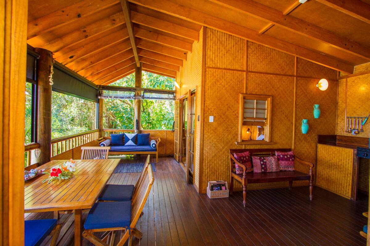 Una terraza de madera con una mesa, bancos y un sofá.