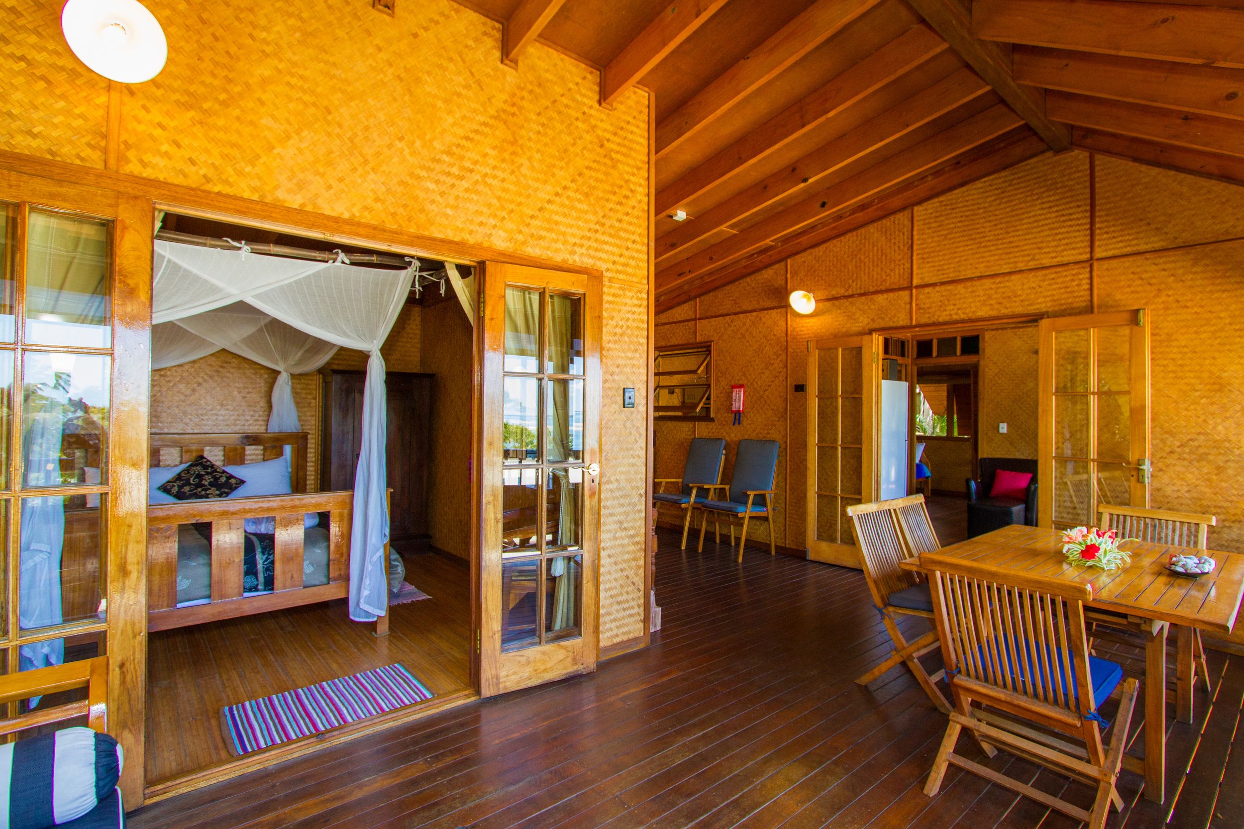 A wooden interior with a bed, chairs, and a table.