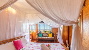 Een kamer met een bed, een bank met kussens en uitzicht op zee.