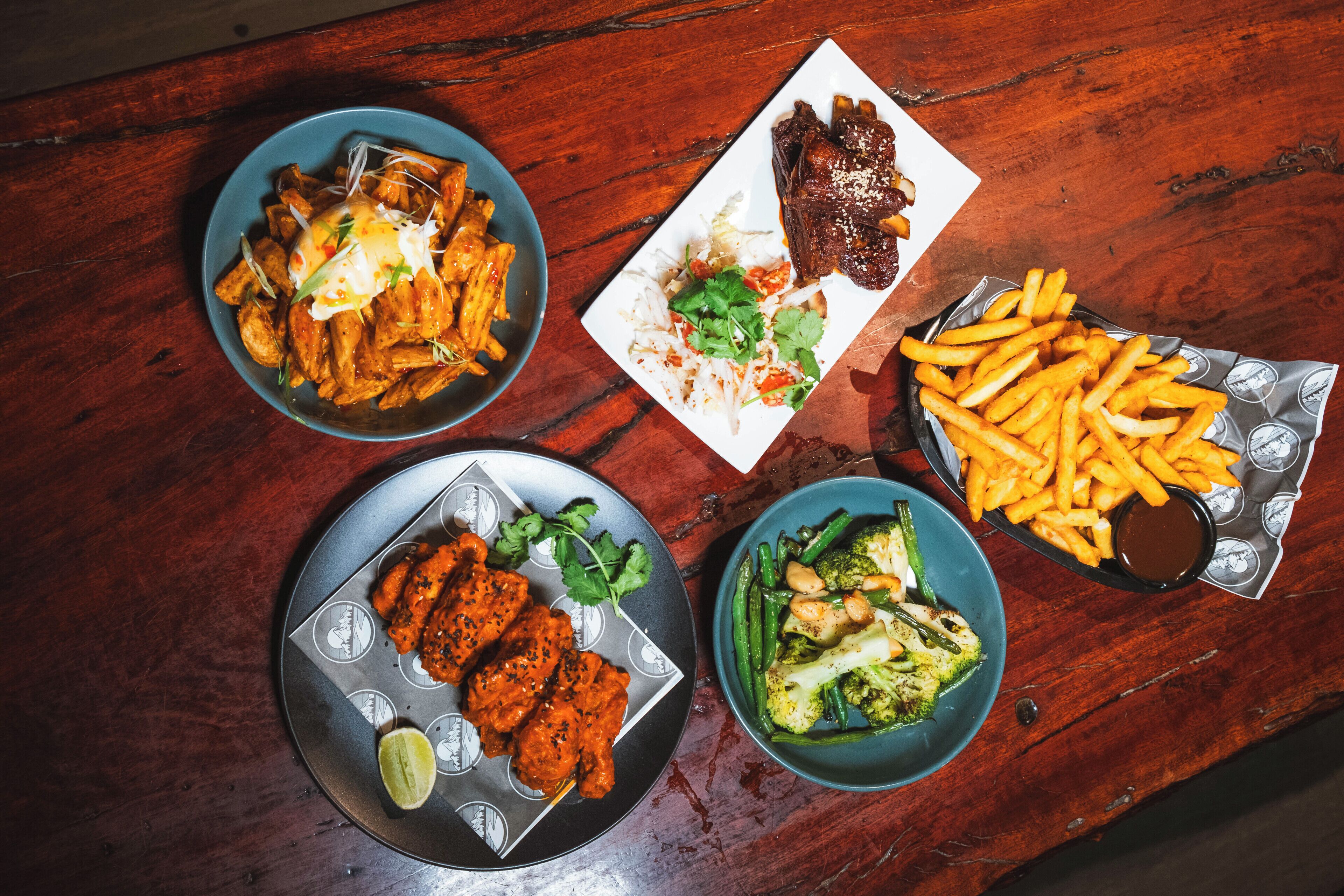 Une table avec différents plats, notamment des frites, un steak et une assiette de salade verte.