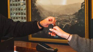 A person handing over a car key to another person at a counter with a payment terminal.