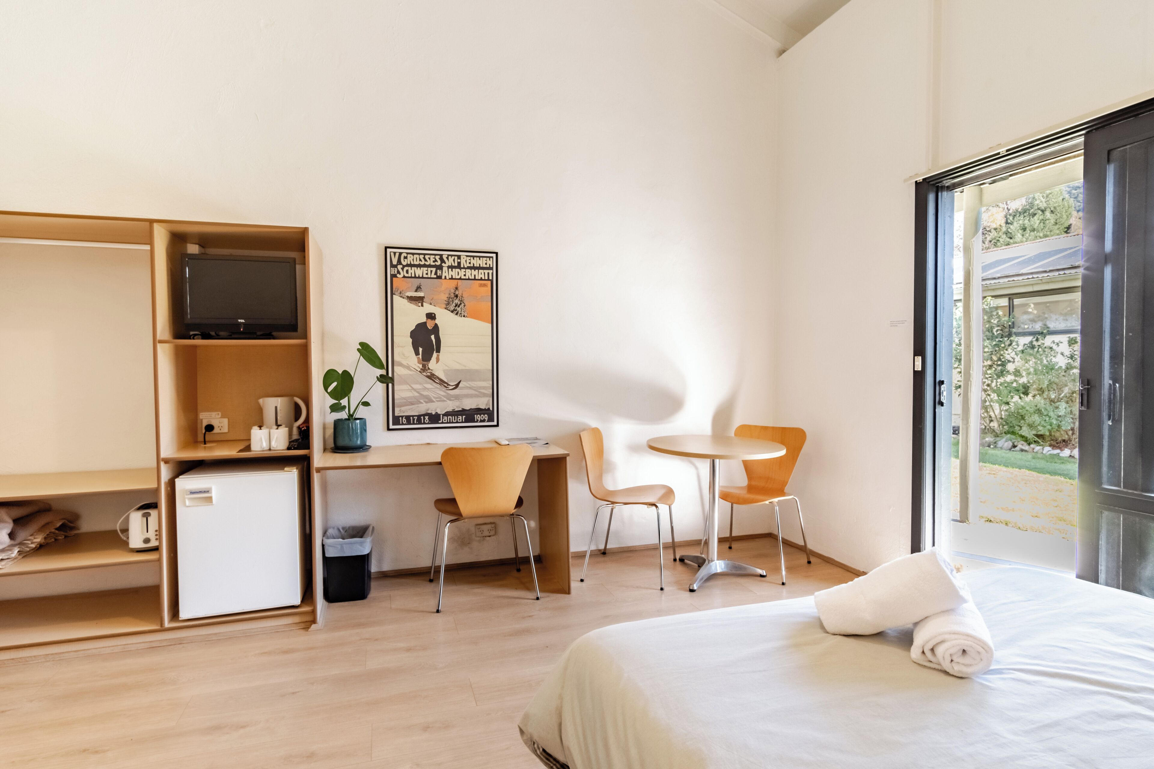 Una habitación de hotel con cama, escritorio, silla, televisión y un cartel en la pared.
