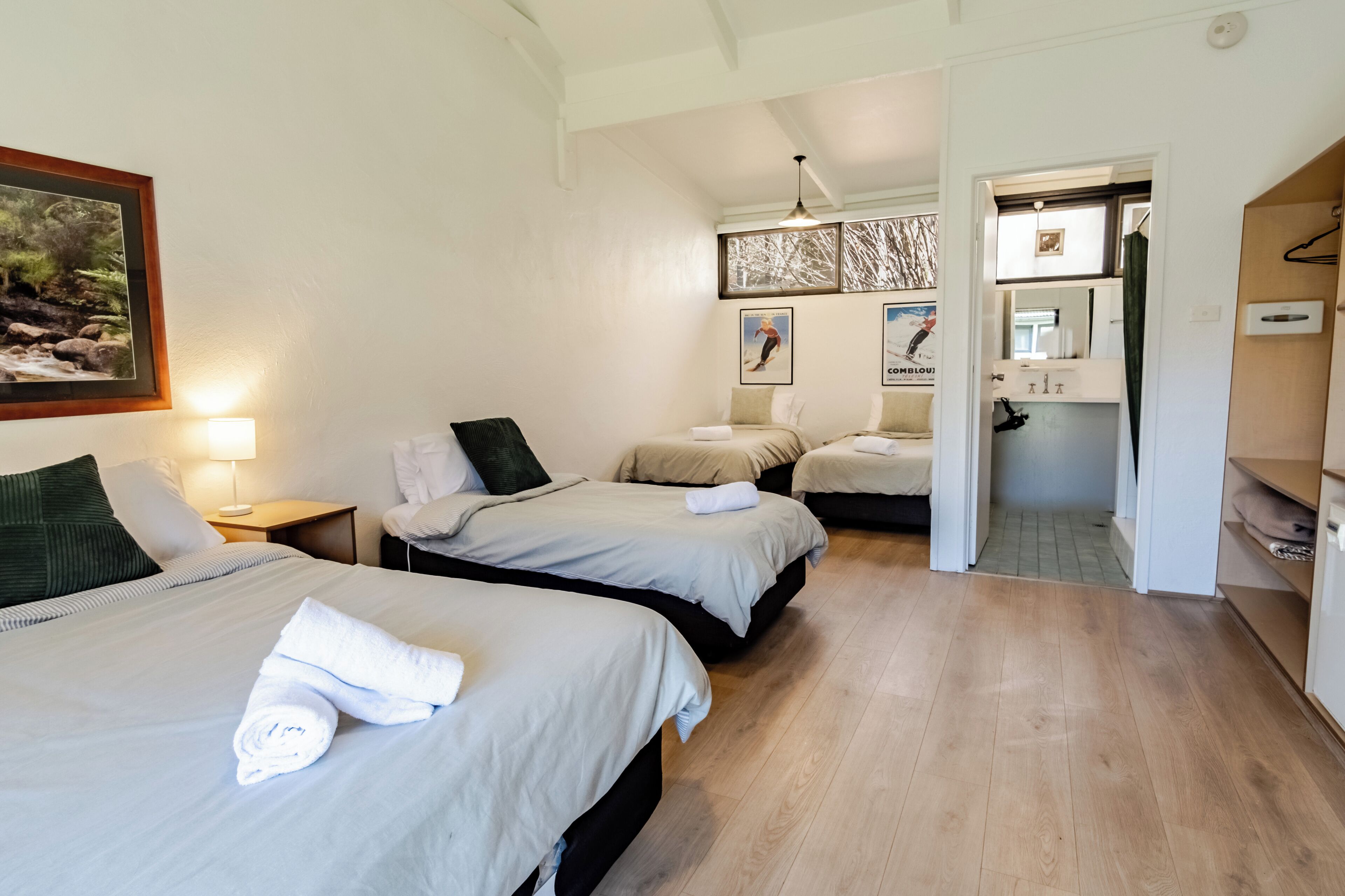 Une chambre d’hôtel avec deux lits, une table de chevet, une lampe et un tableau au mur.