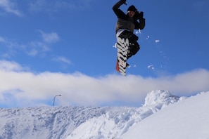 Un snowboarder en plein saut, en l’air, sur une pente enneigée.