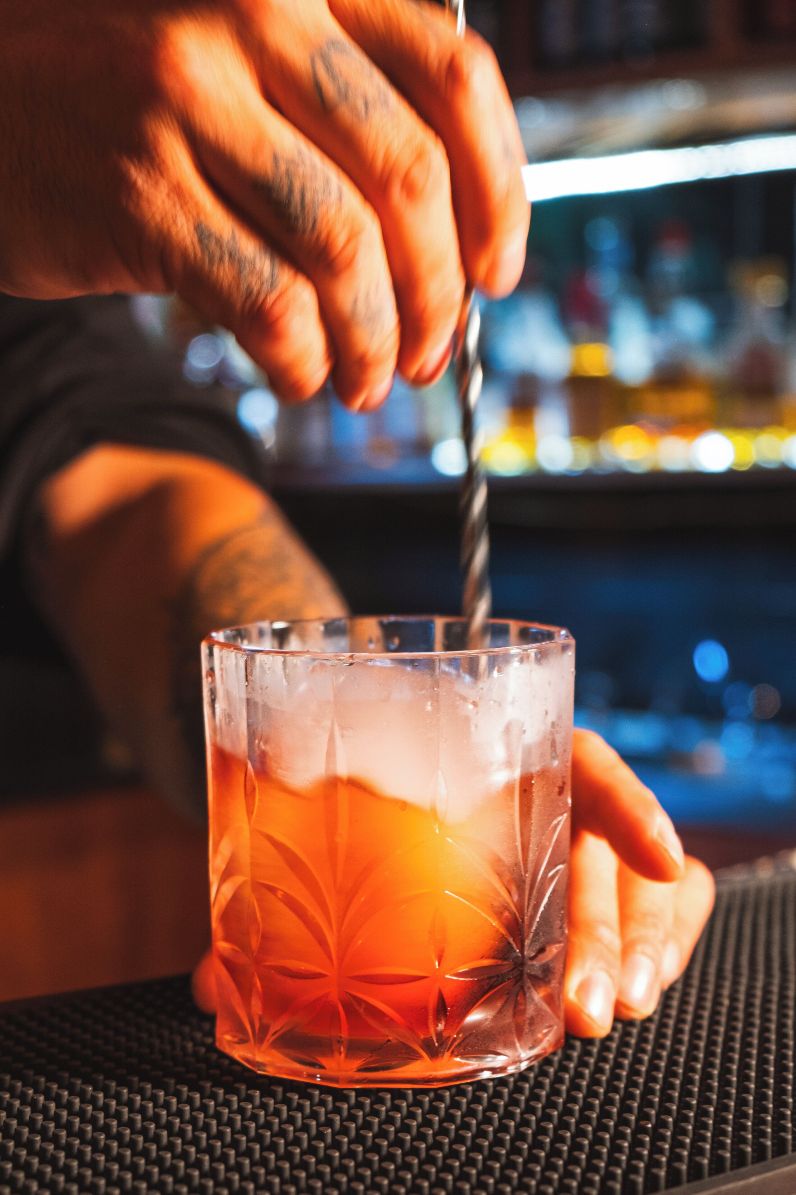 A person pouring a drink into a glass with a decorative pattern.