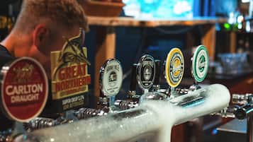 Una llave de grifo de bar con varias etiquetas de cerveza, incluyendo 'Carlton Draught' y 'Great Northern'.