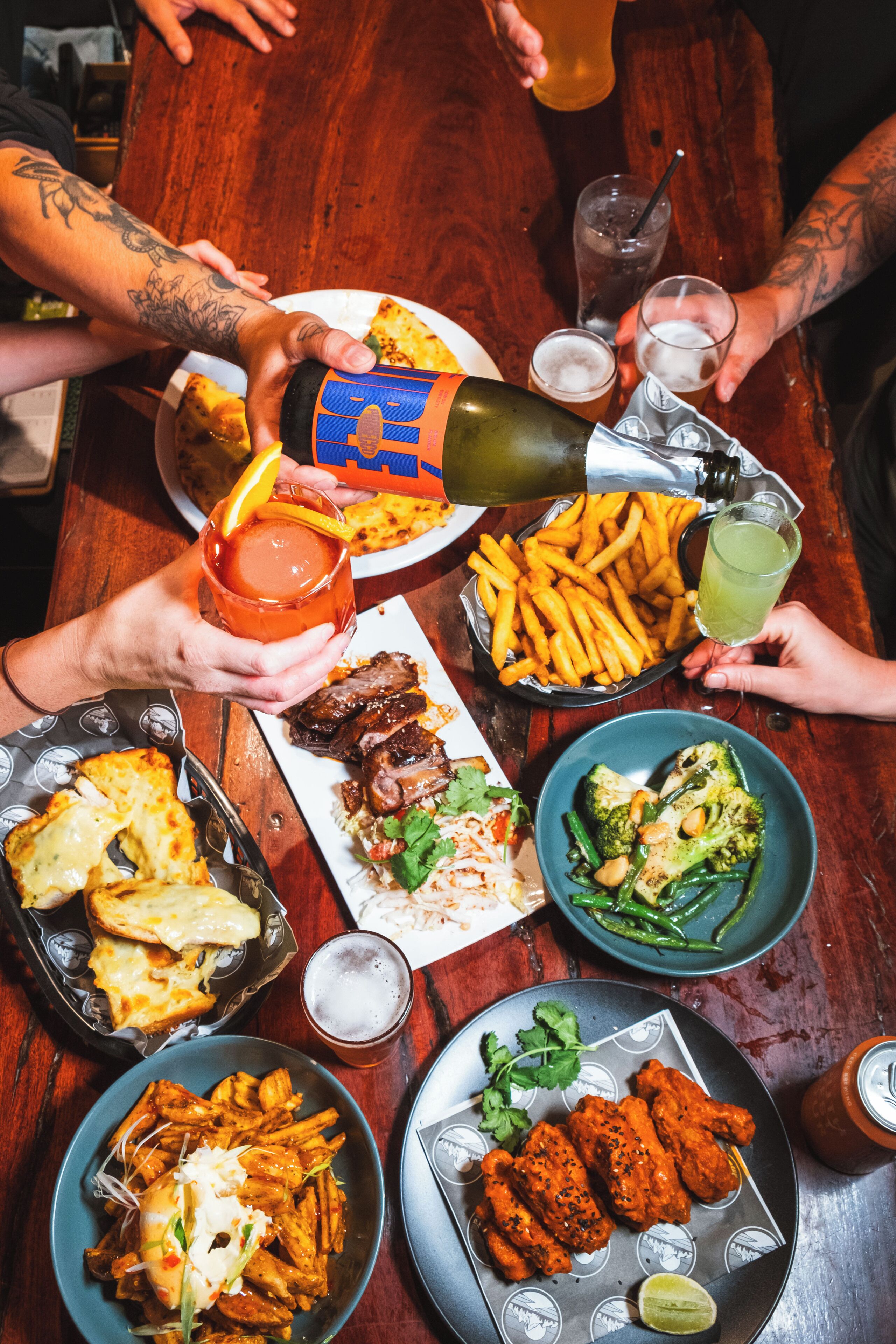 A group of people dining at a restaurant with various dishes including fries, wings, and a burger.