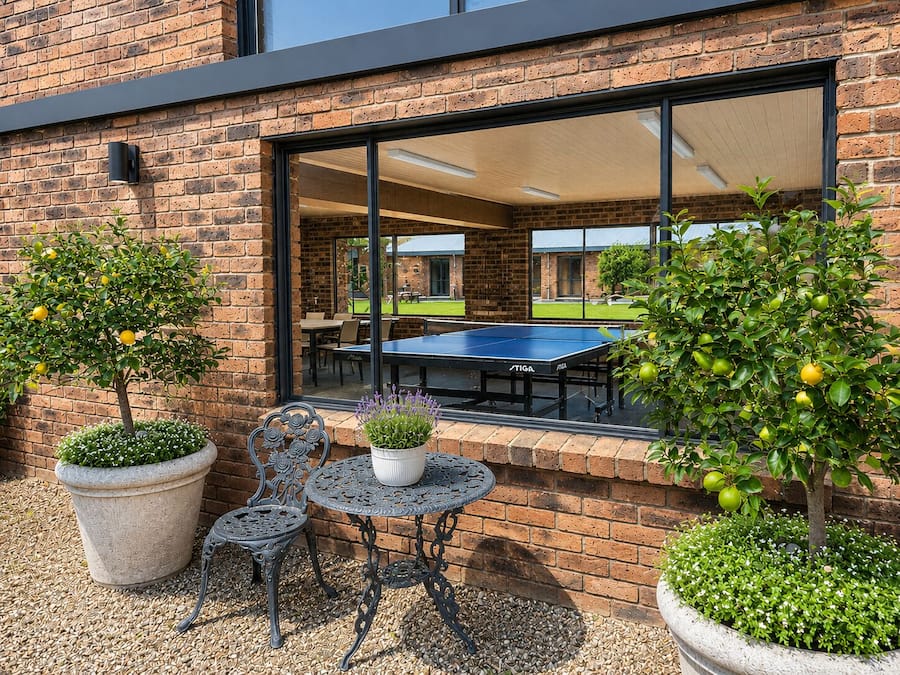 A patio with a ping pong table, two chairs, and potted plants.