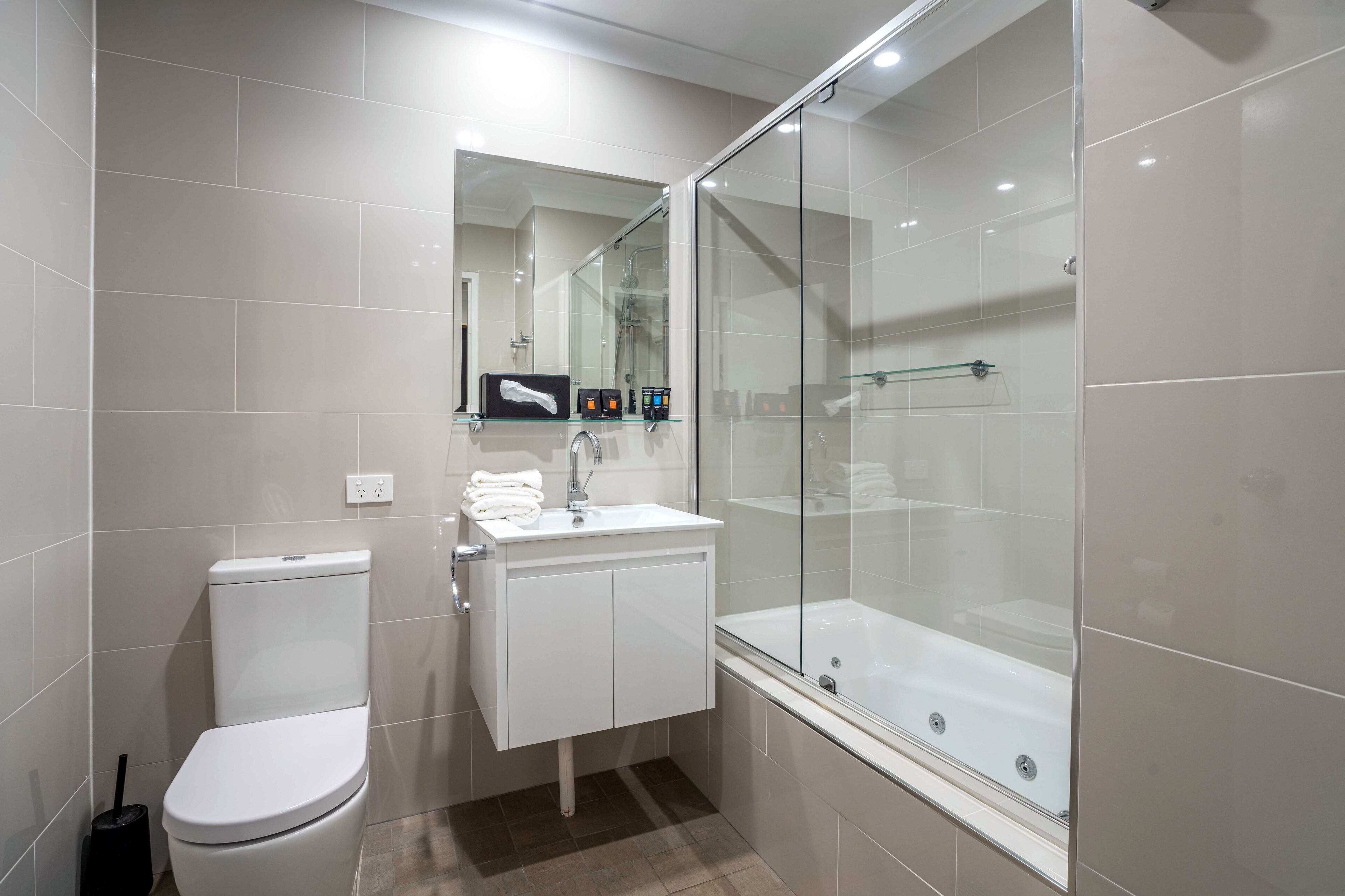 Un baño moderno con inodoro, lavamanos y ducha de vidrio.