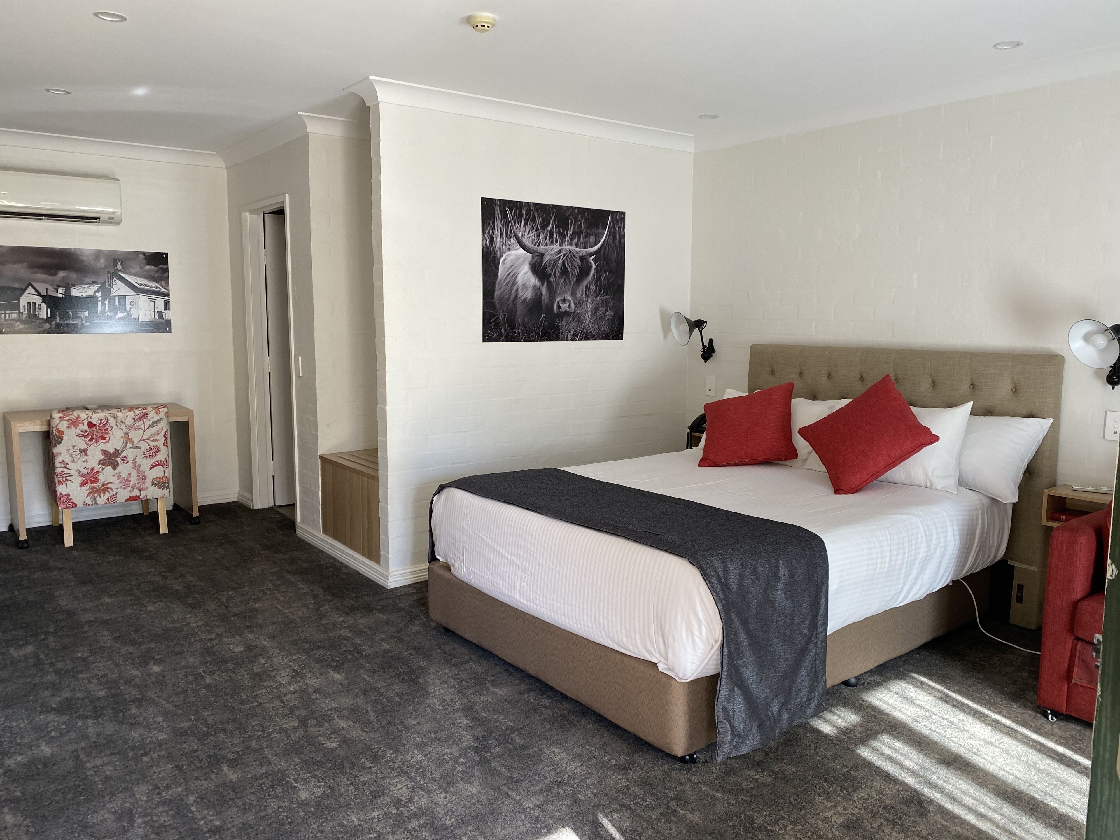 Une chambre d’hôtel moderne avec un grand lit, un petit bureau et un climatiseur fixé au mur.