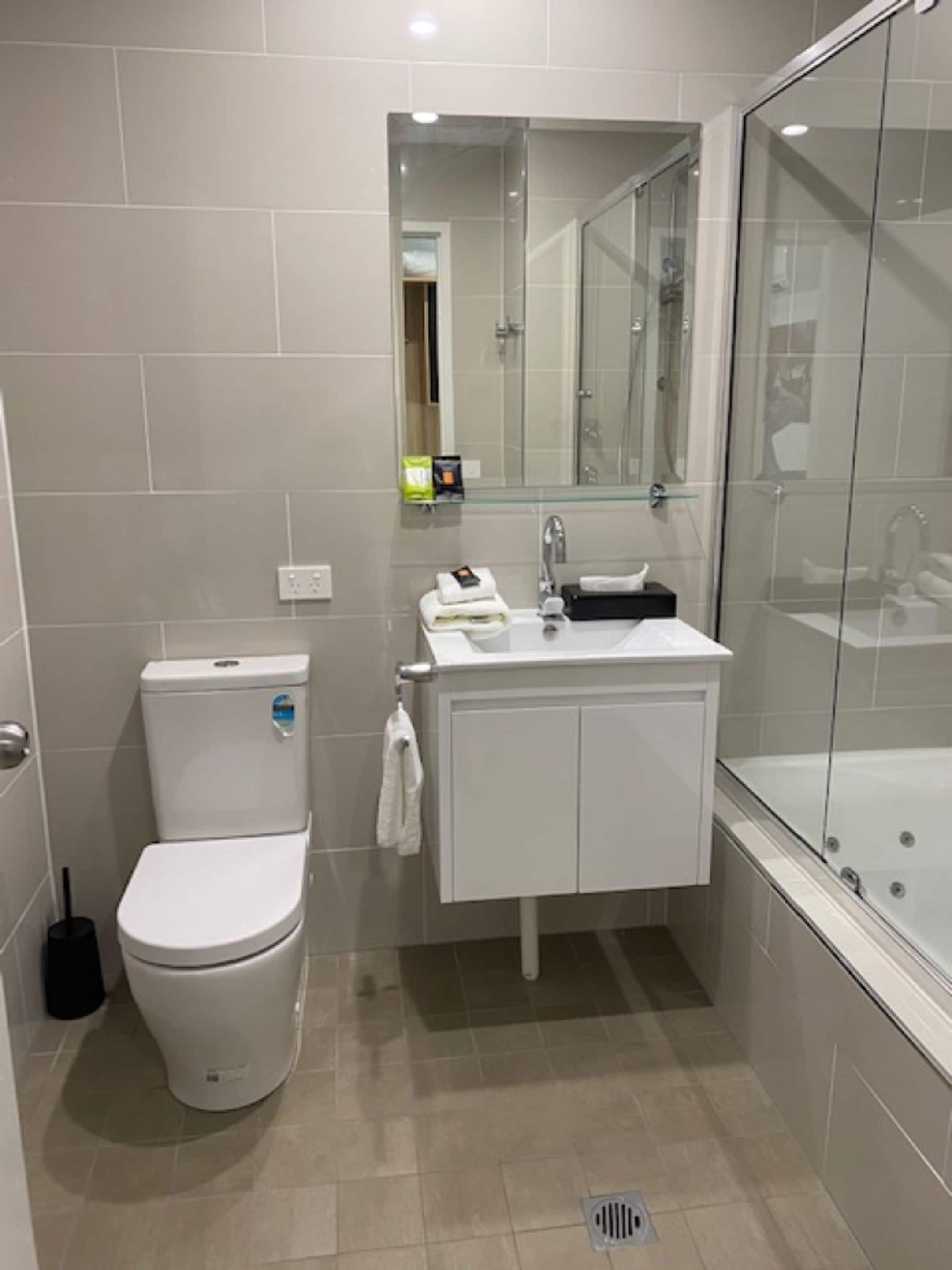 A modern bathroom with a toilet, sink, and glass-enclosed shower.
