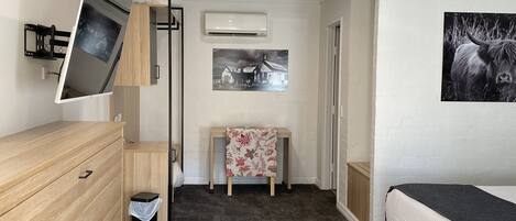 A modern bedroom with a bed, a dresser, a desk, and a small table with a floral tablecloth.