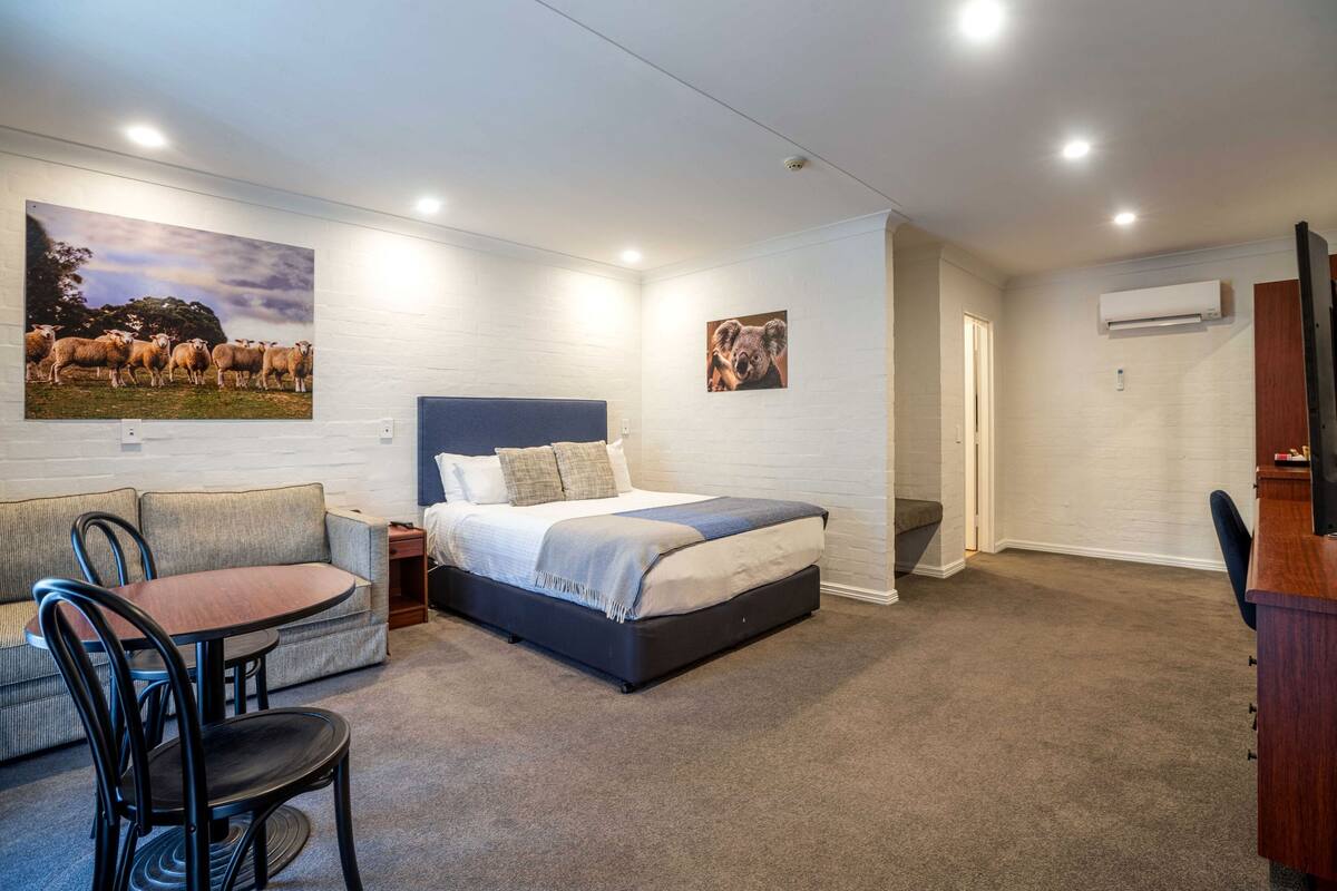 Un dormitorio con una cama, un sofá, una mesa de comedor y sillas.