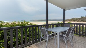 Un espacio al aire libre techado con una mesa y sillas, con vistas a una playa y al océano.