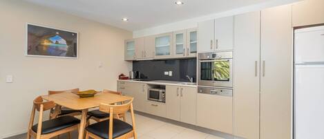 Una cocina moderna con una mesa de comedor y sillas, un refrigerador, horno, microondas y armarios.
