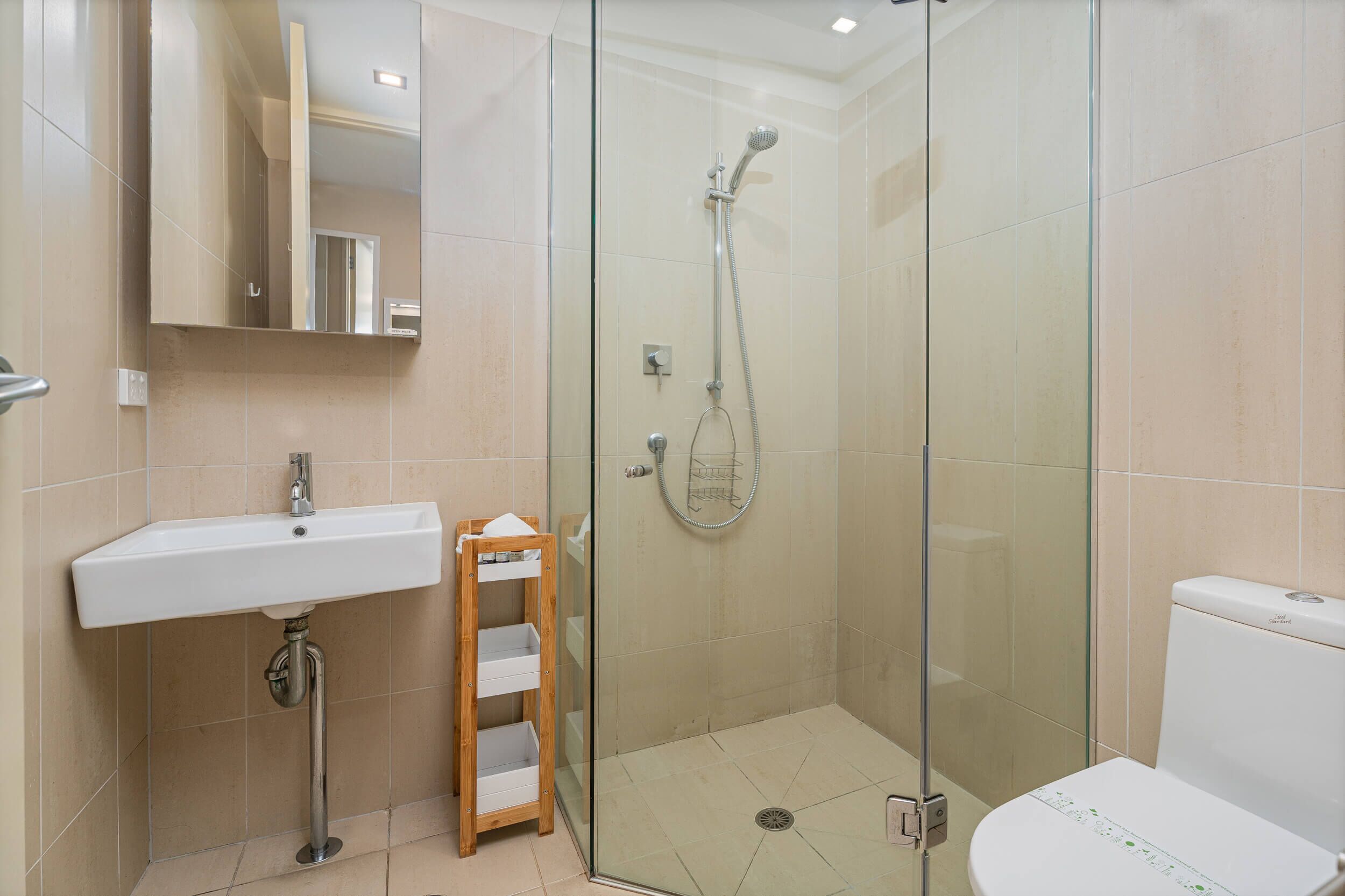 Ein modernes Badezimmer mit einer gläsernen Duschkabine, einem weißen Waschbecken und einer Toilette.