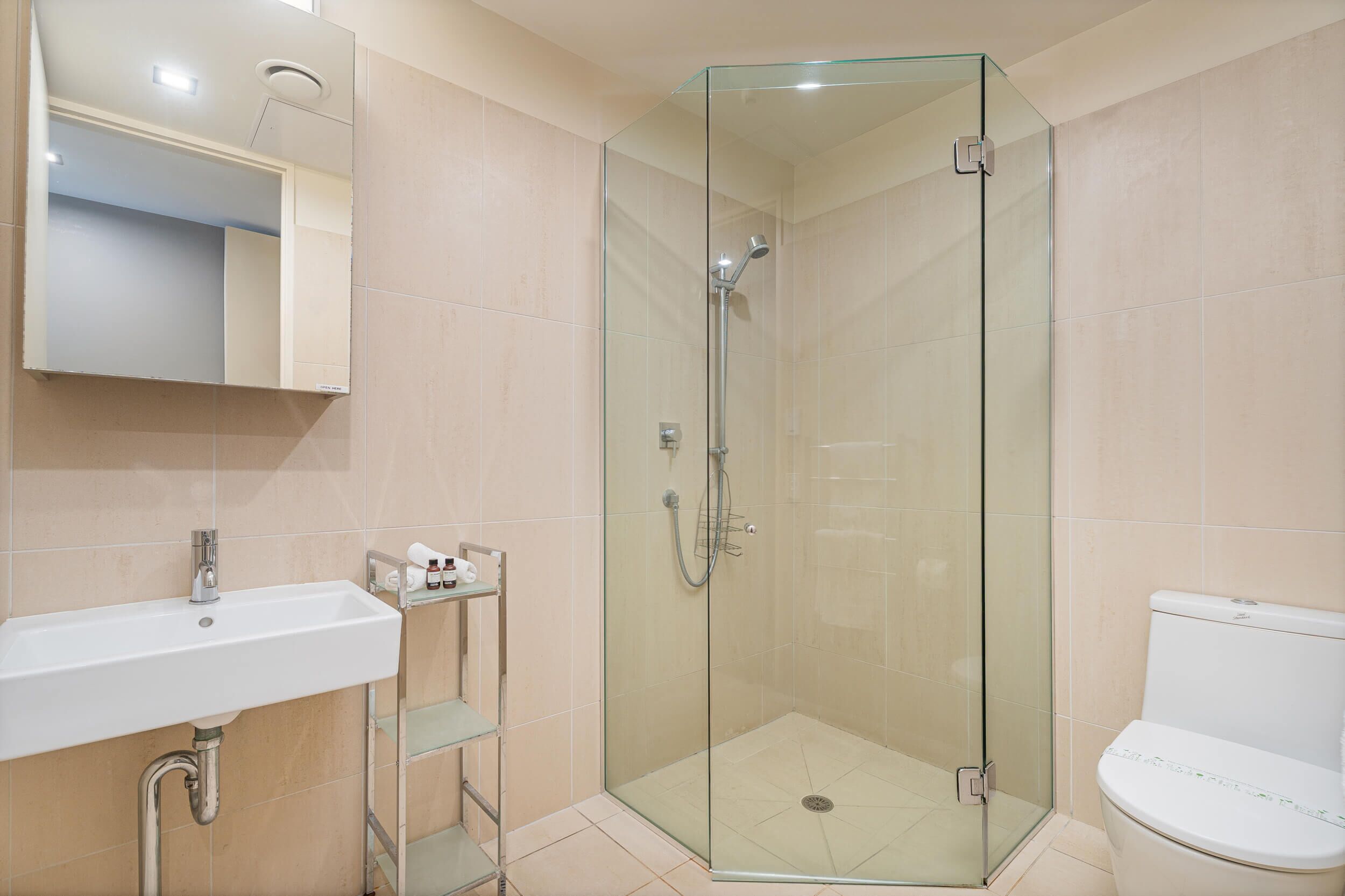 A bathroom with a glass-enclosed shower, a sink, and a toilet.