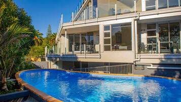 A modern building with a swimming pool, large windows, and outdoor seating.