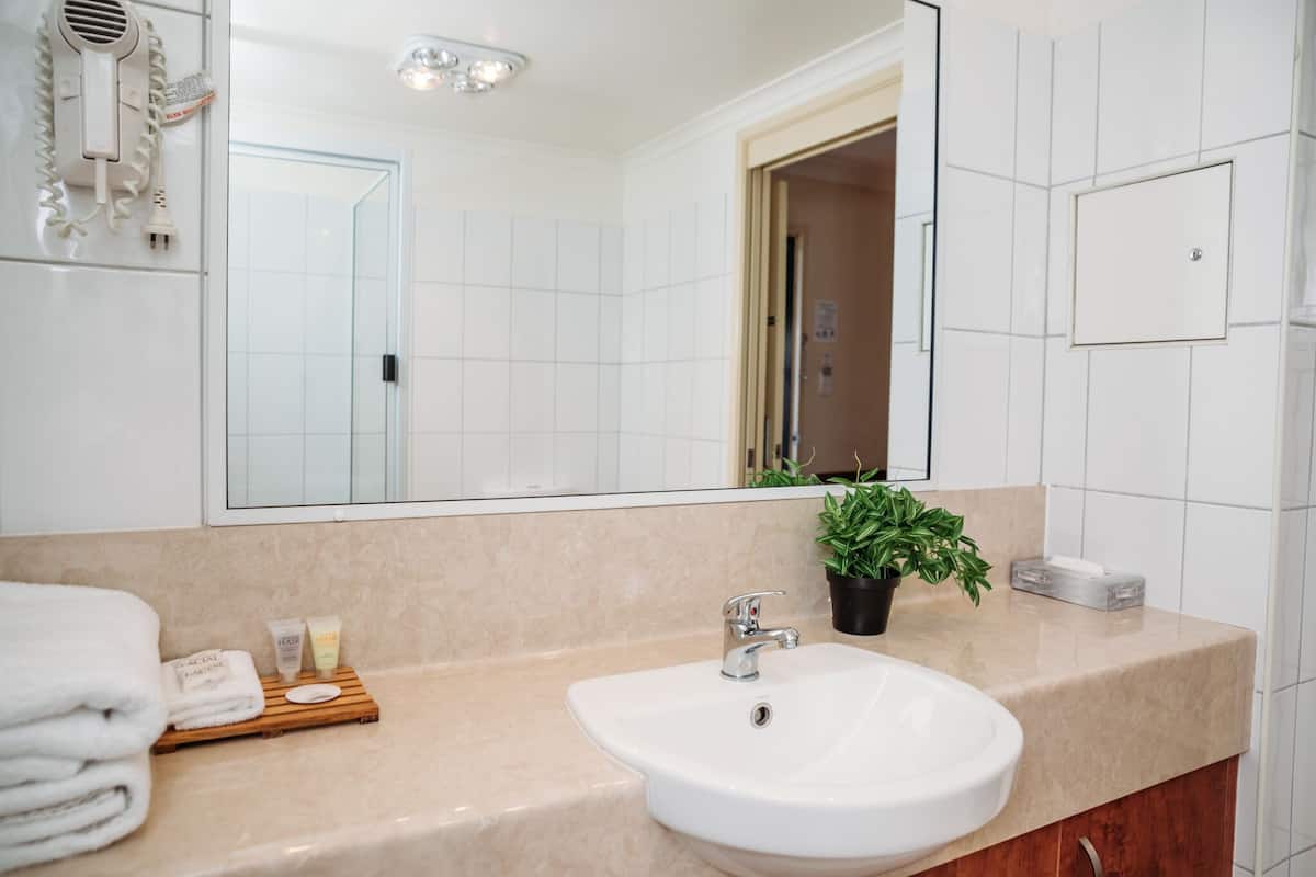 Une salle de bain moderne avec un grand miroir, des carreaux blancs, un lavabo et un porte-serviettes.