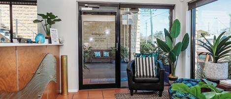 A reception area with a glass door, a black leather sofa, and a patterned rug.