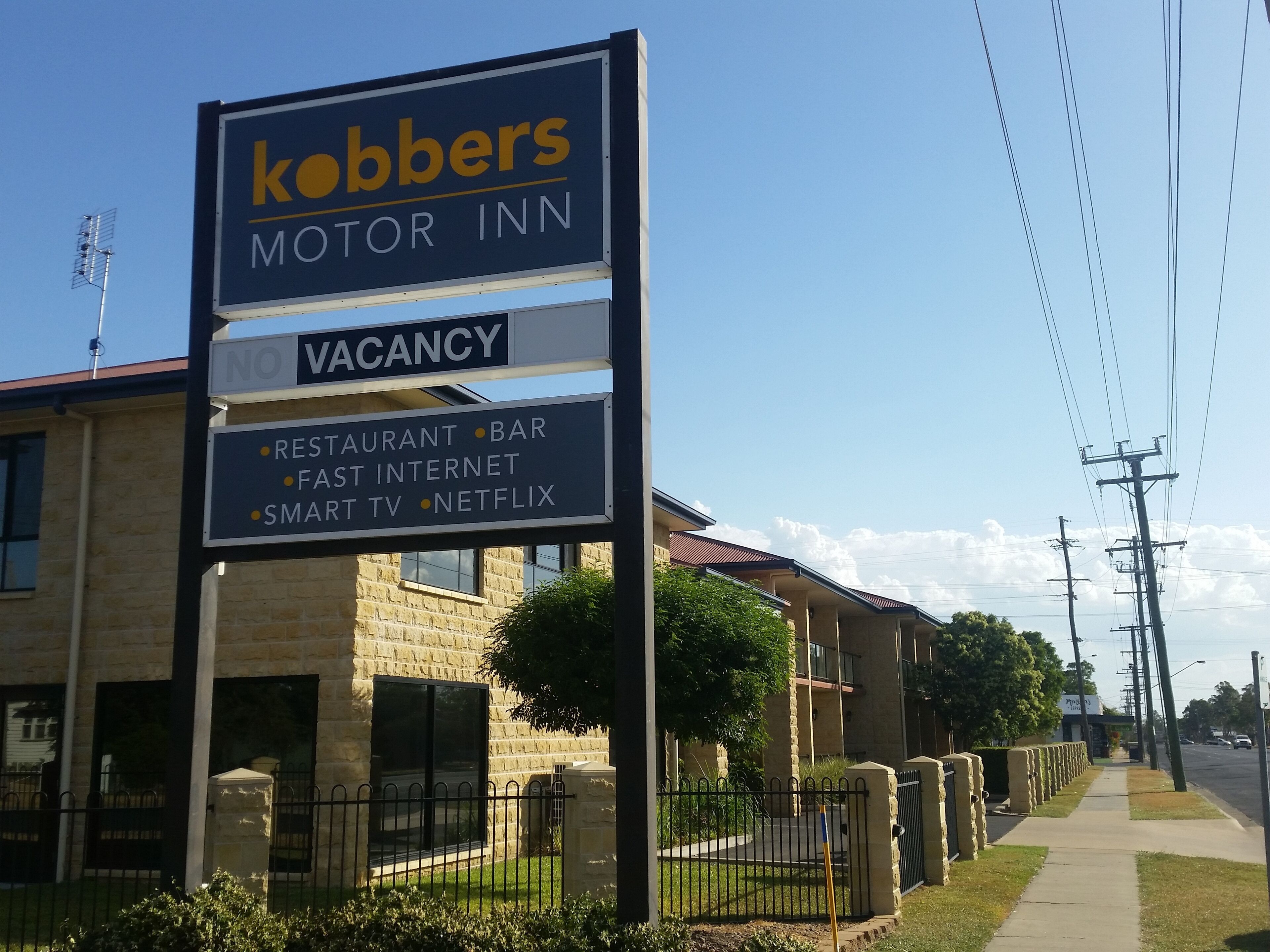 A sign for 'Kobbers Motor Inn' with amenities including a restaurant, bar, fast internet, smart TV, and Netflix.