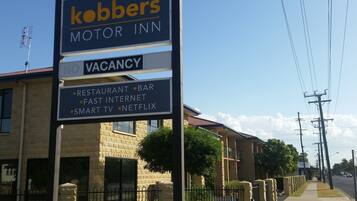 A sign for 'Kobbers Motor Inn' with amenities including a restaurant, bar, fast internet, smart TV, and Netflix.