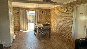 A room with a dining table, chairs, a ceiling fan, a clock on the wall, and a door labeled 'Staff Only'. - Starlight Motor Inn (Roma)