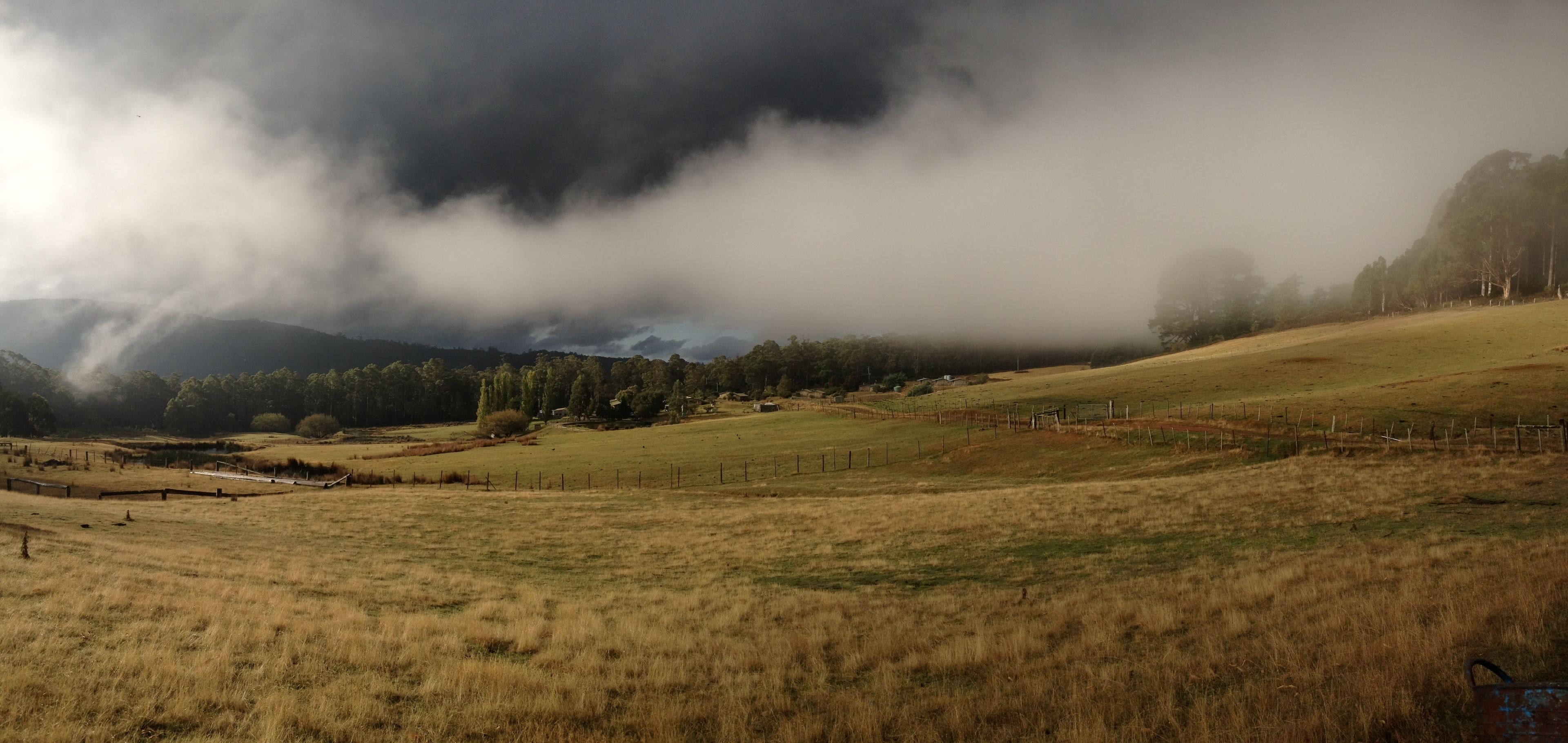 A rural landscape with a field, a fence, and a distant mountain range.