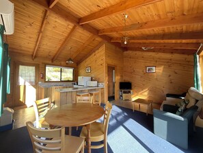 A wooden cabin interior with a kitchen, dining area, and living room.