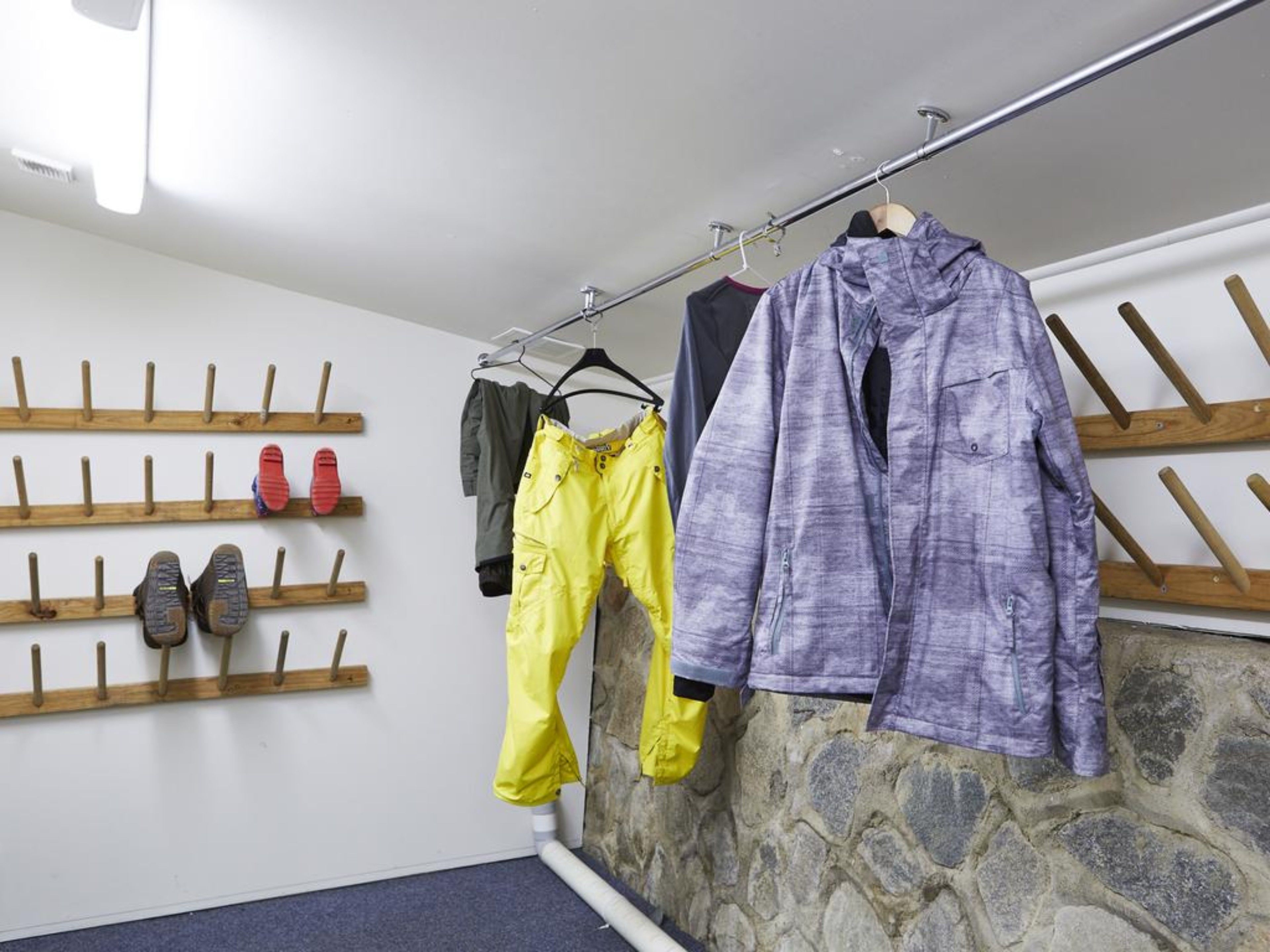 A storage area with wooden shoe racks and a stone wall.