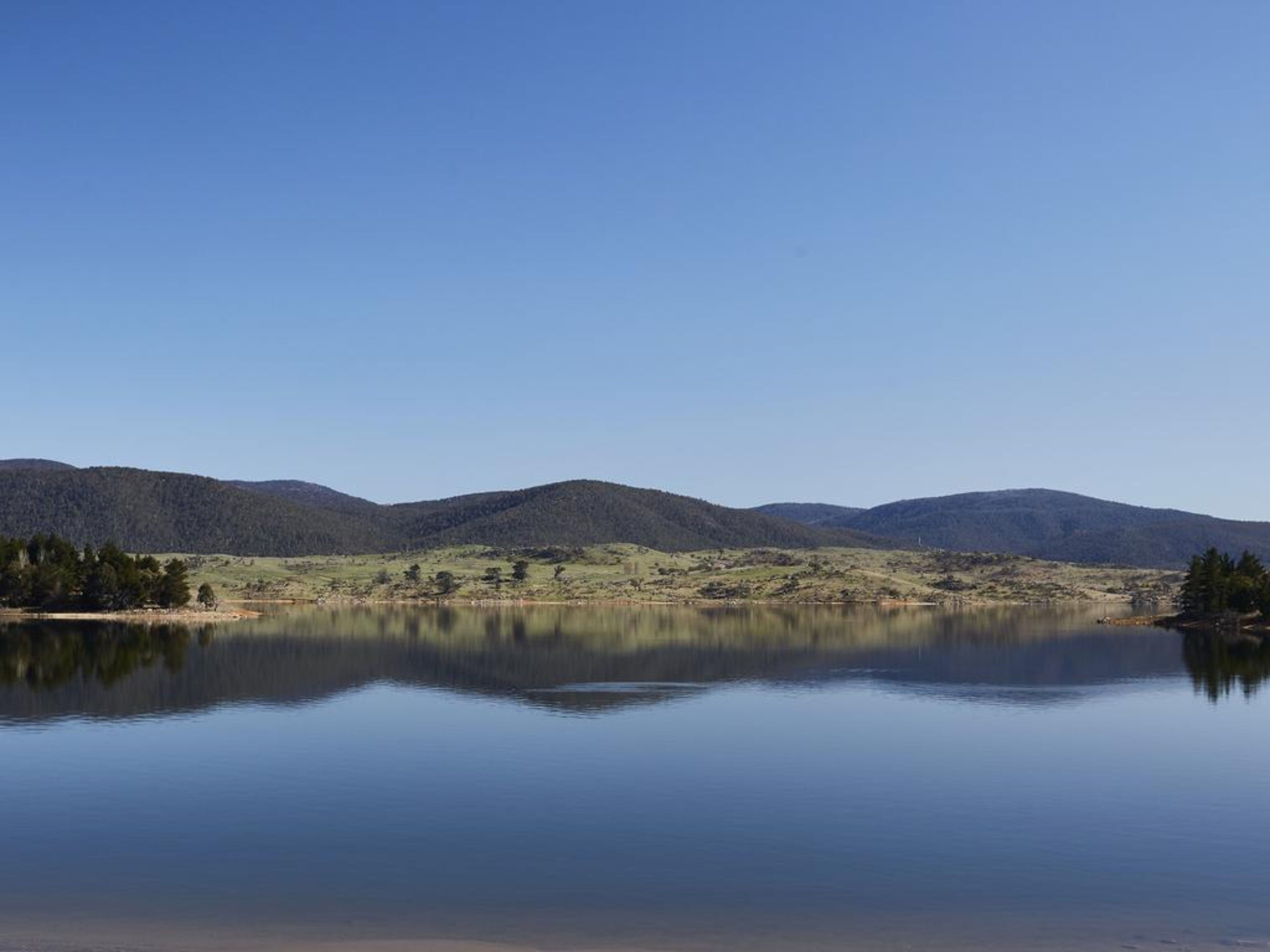 A calm lake with mountains in the background.