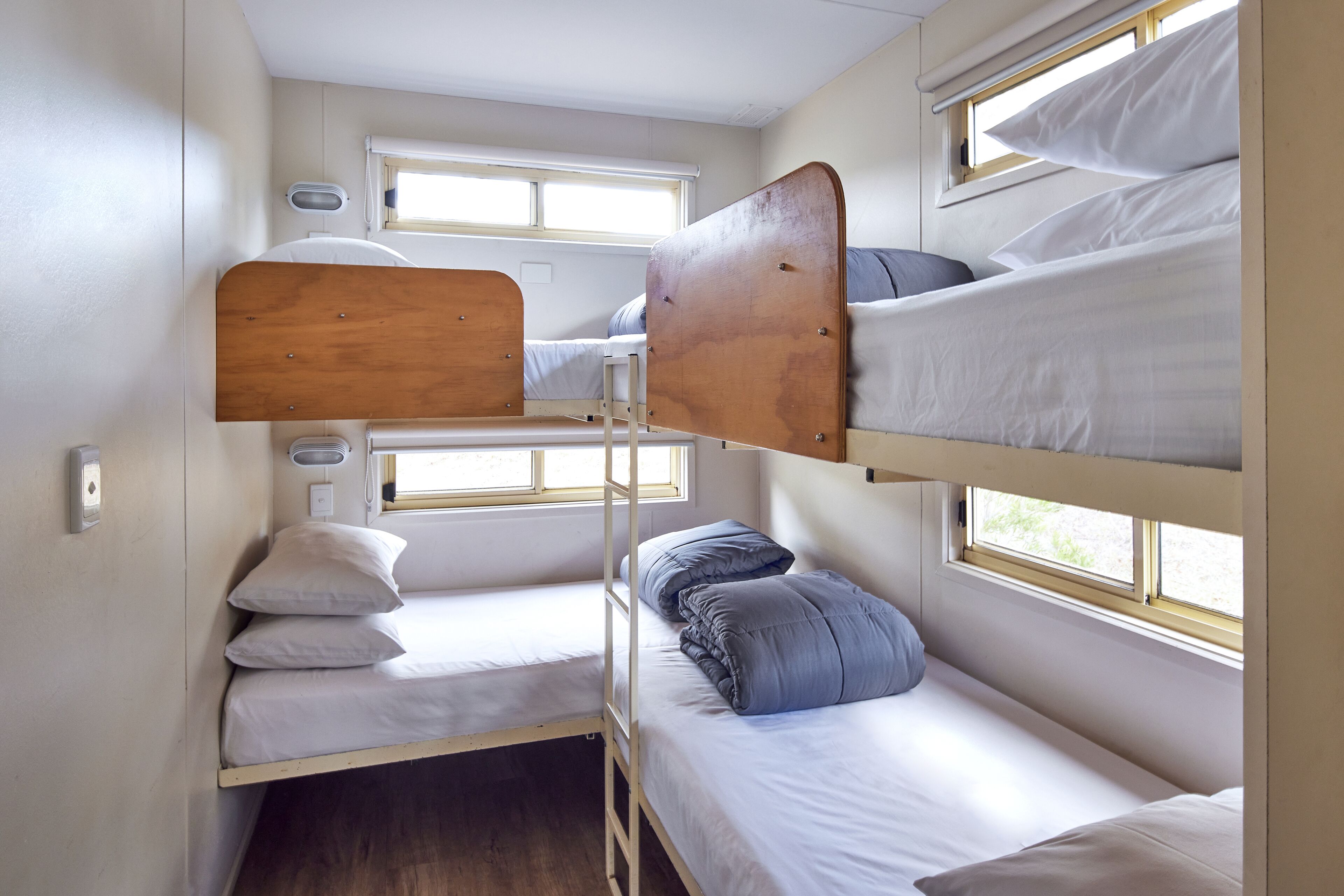 A bunk bed room with a window, a small table, and a power outlet.