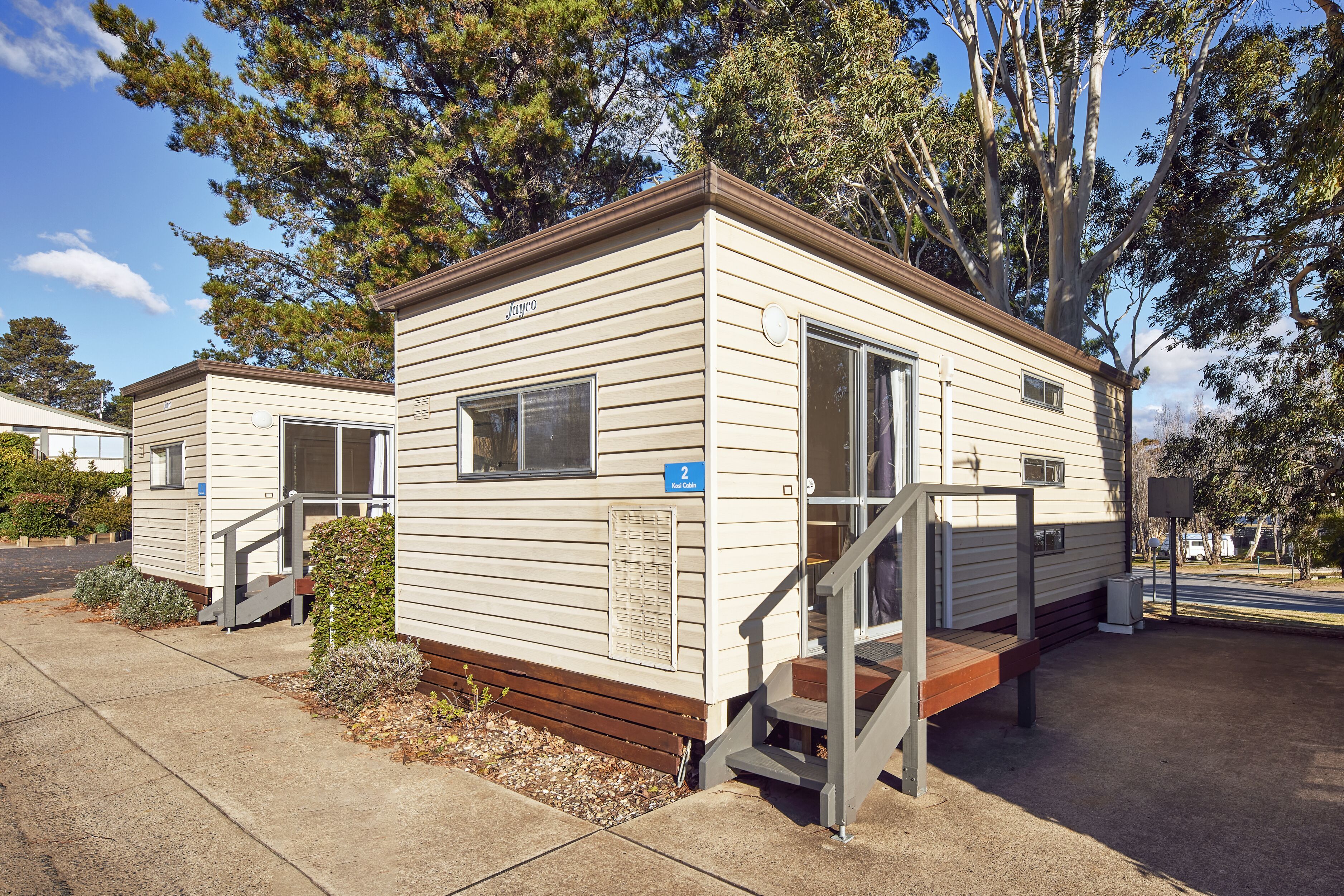 A mobile home with a wooden deck and a small staircase leading to the entrance.