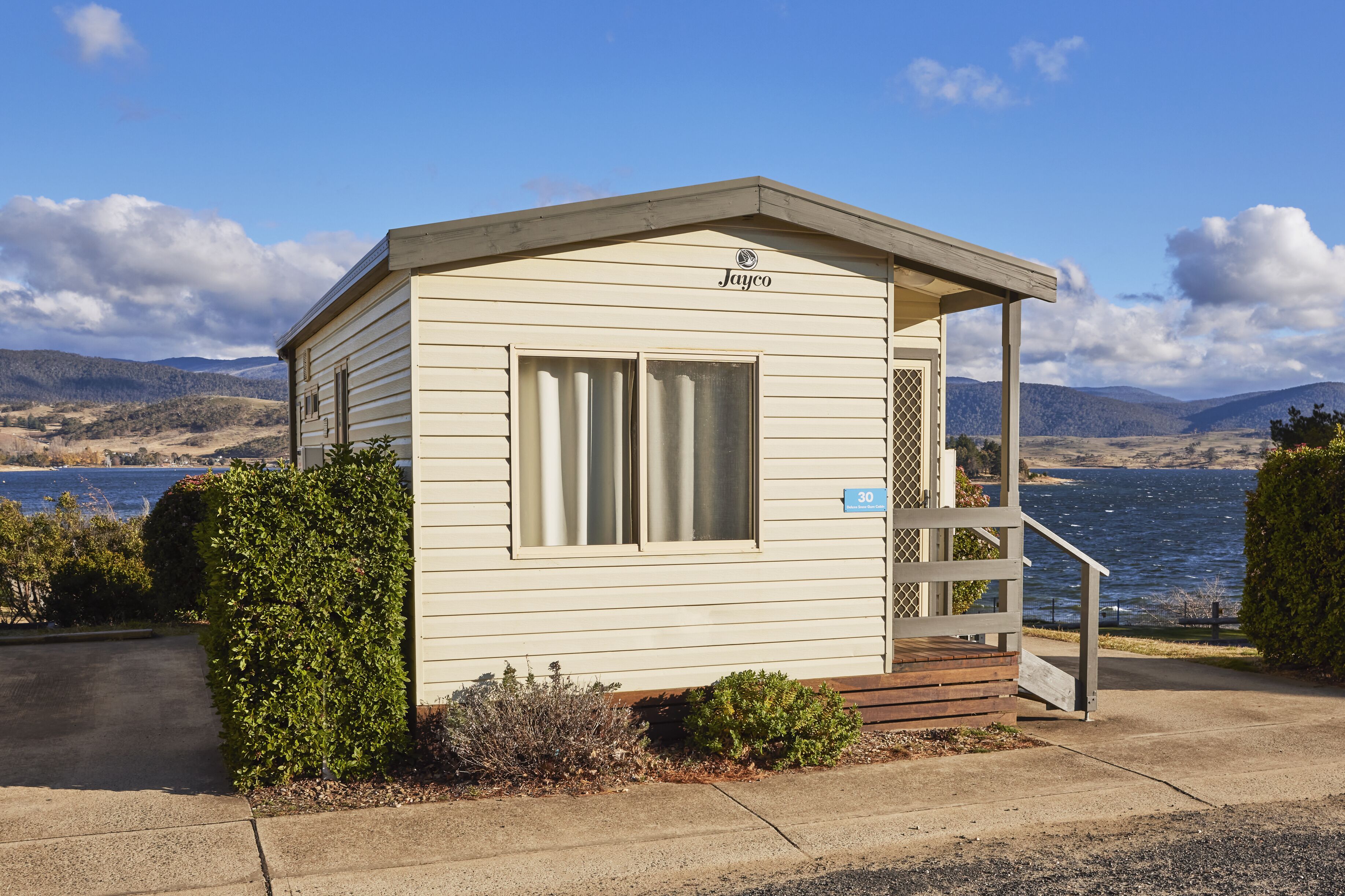 A small, single-story building with a nameplate reading "Jayco" and a number "30" sign. It features a covered porch with steps leading up to it.