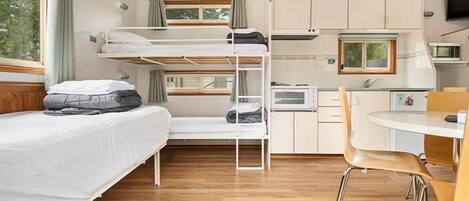 A compact room with bunk beds, a kitchenette, and a dining area.