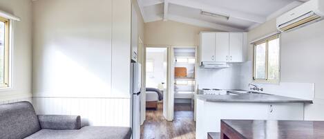 Una cocina moderna con armarios blancos, encimera de madera y ventilador de techo.