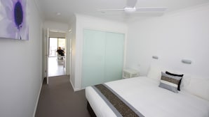 Habitación de hotel con cama, ventilador de techo, armario y un cuadro en la pared.